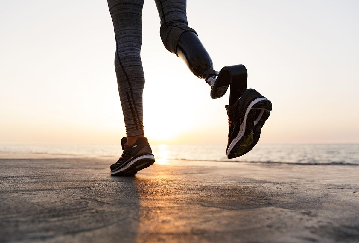 En funktionshindrad kvinna joggar på stranden