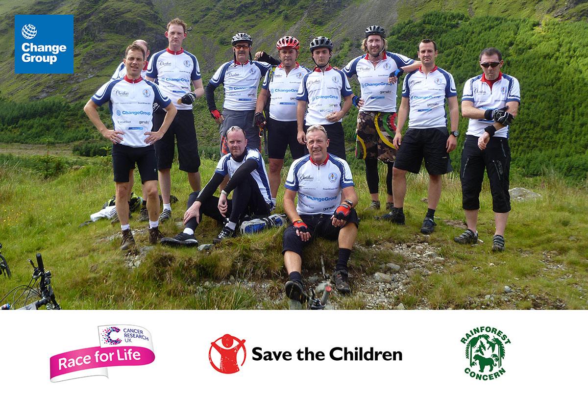 En grupp cyklister poserar på landsbygden med logotyperna för ChangeGroup, Race for Life och Save the Children.