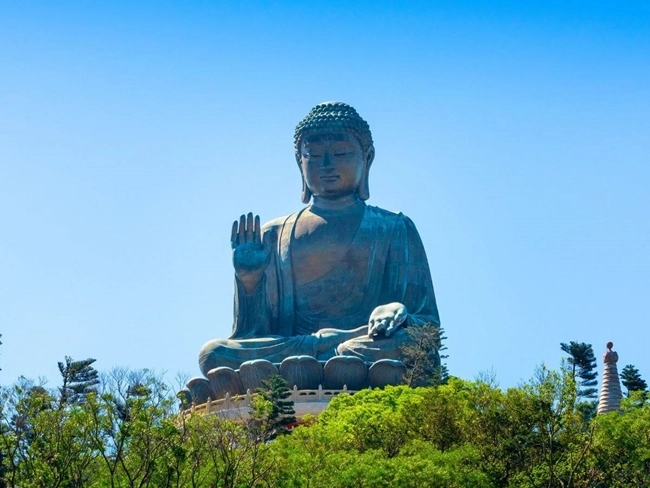 En Buddhastaty under bar himmel med utsikt över en skog