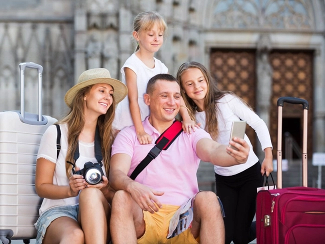 En familj på semester tar en selfie bredvid sina resväskor