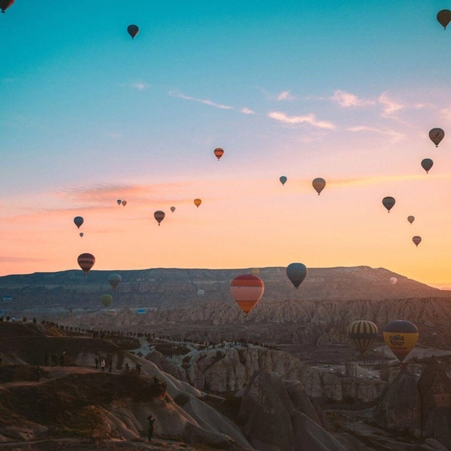 Många varmluftsballonger i skyn över bergen i Turkiet